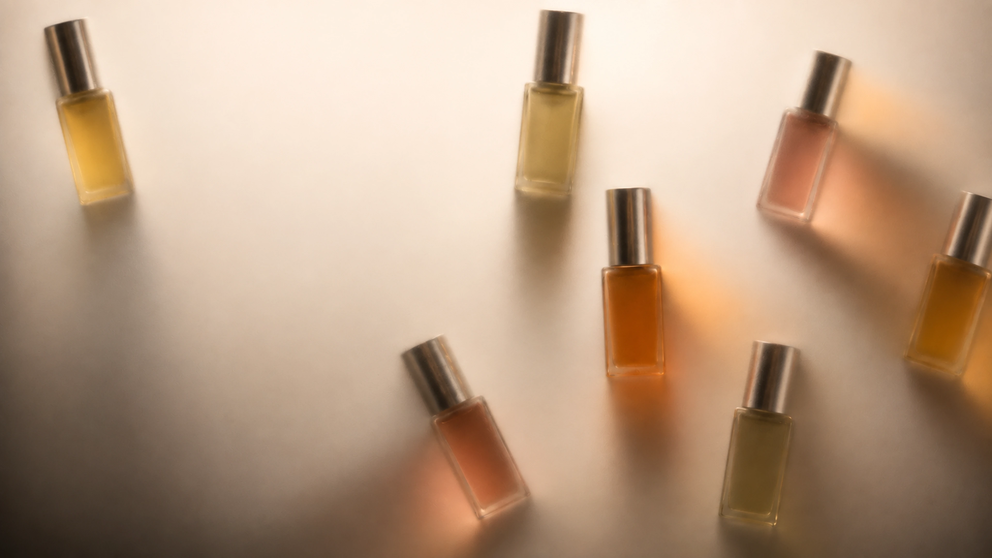 Colorful SabbyScents decant silhouettes glowing behind smooth warm frosted glass